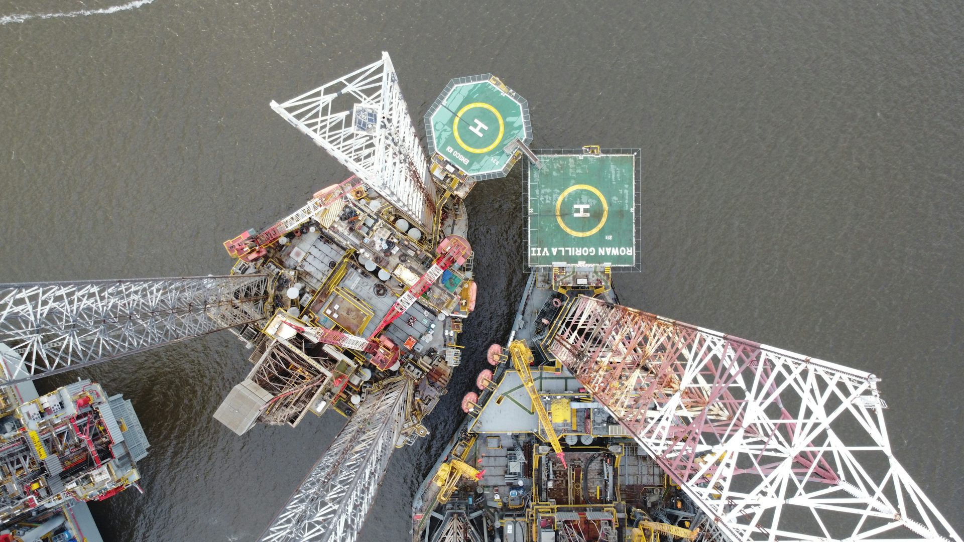 aerial shot looking down at oil rig, helicopter pads and grey ocean