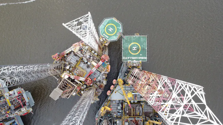 aerial shot looking down at oil rig, helicopter pads and grey ocean