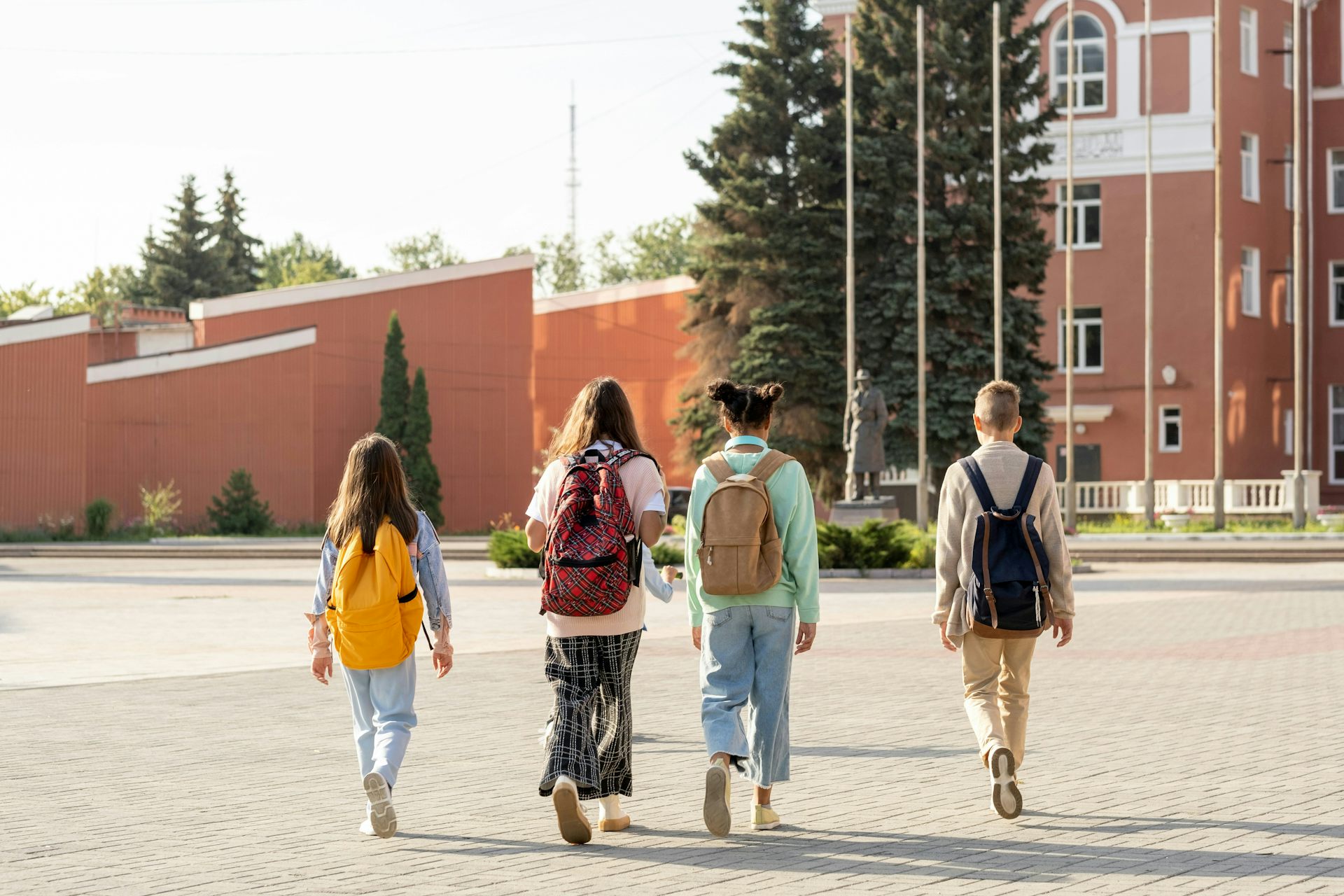 four kids wearing backpacks walking 