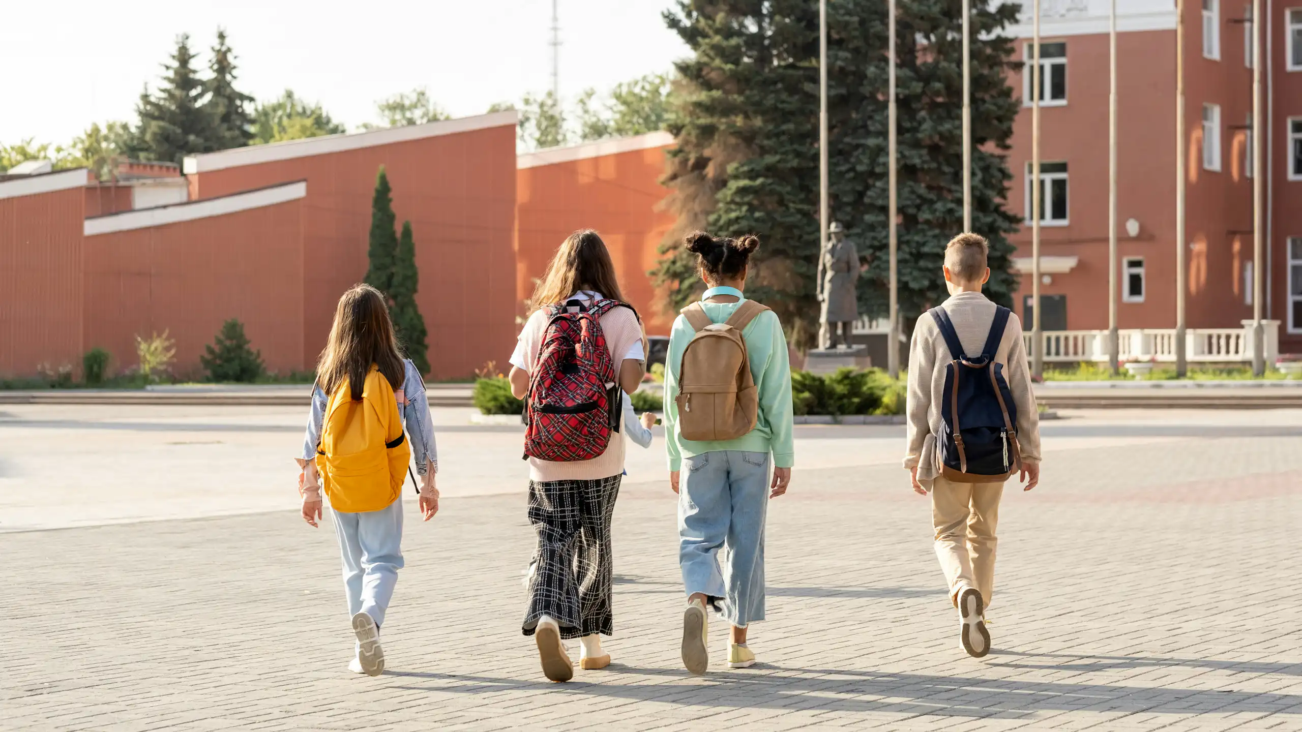 four kids wearing backpacks walking