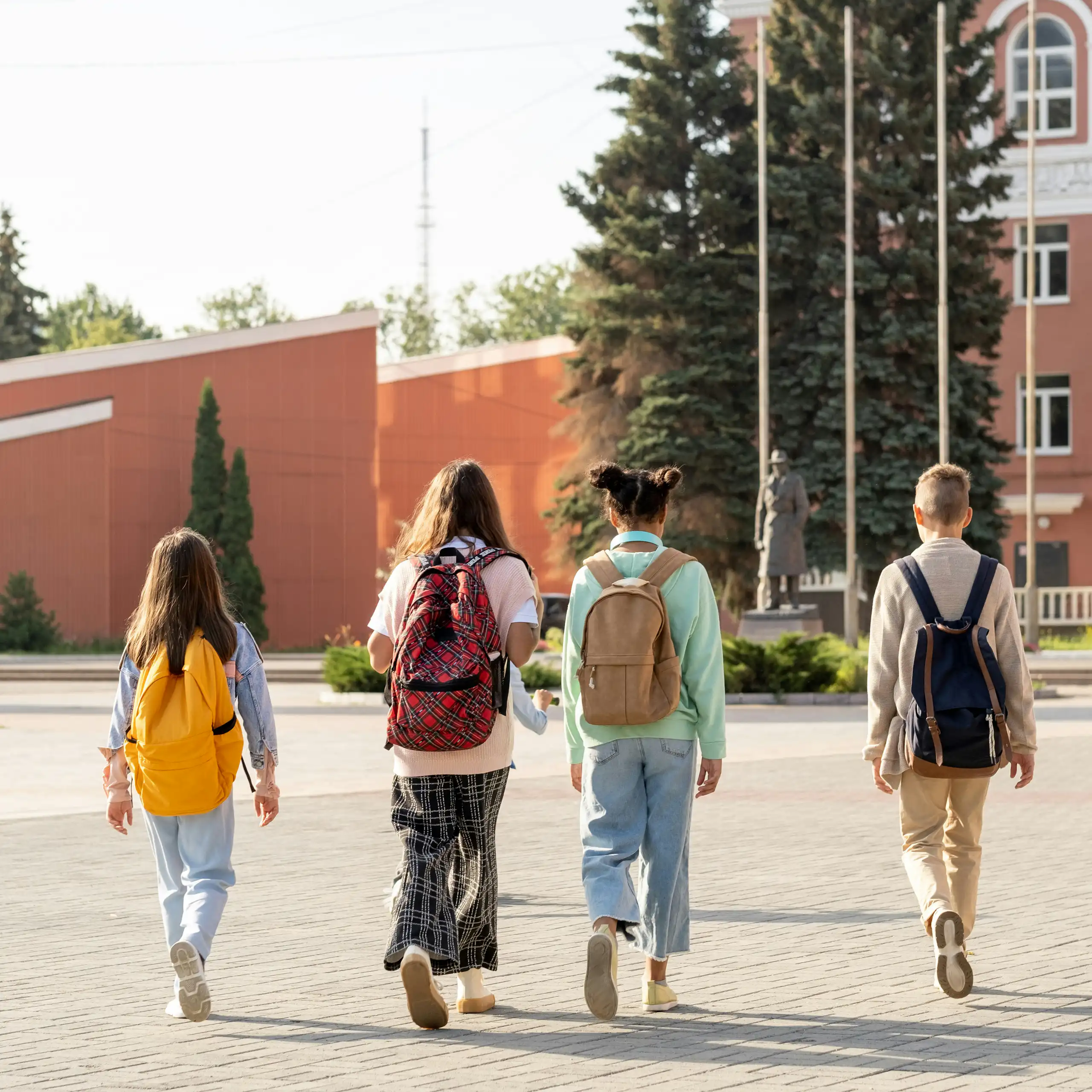 four kids wearing backpacks walking