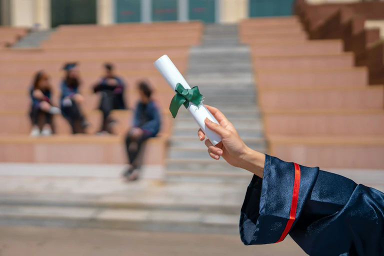 A hand holding up a rolled diploma.