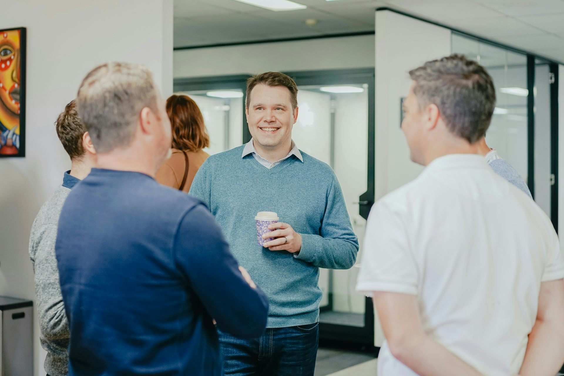 A group of people chatting around a water cooler