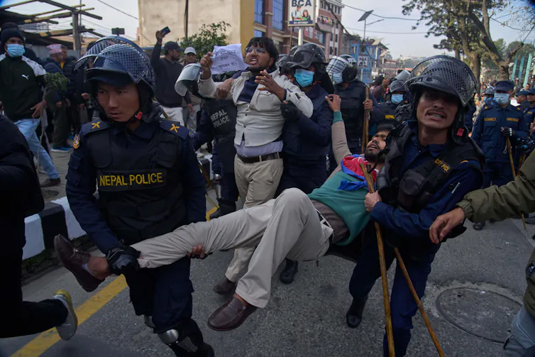 A young man is being carried away by police for protesting.
