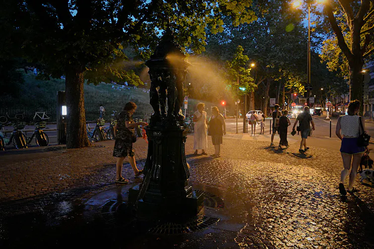 people cooling off in evening using a misting fountain.