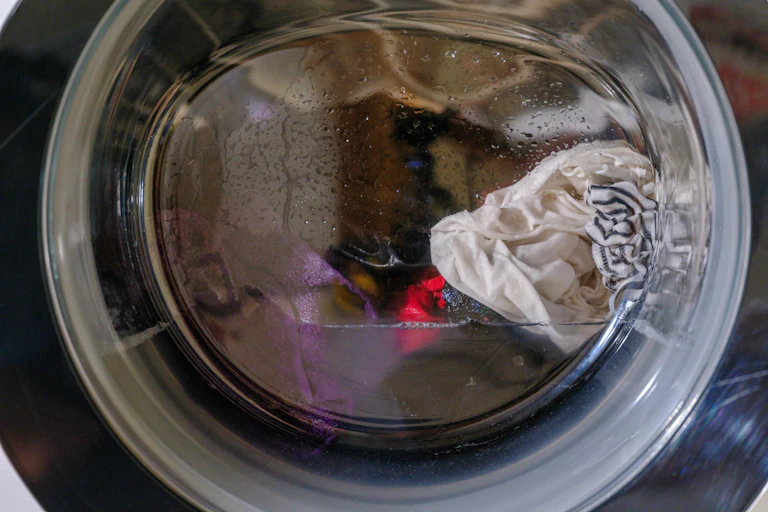Close-up of wet laundry in a front-loading washing machine.
