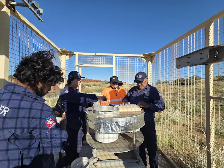 A group of four rangers change equipment in a grassland area.