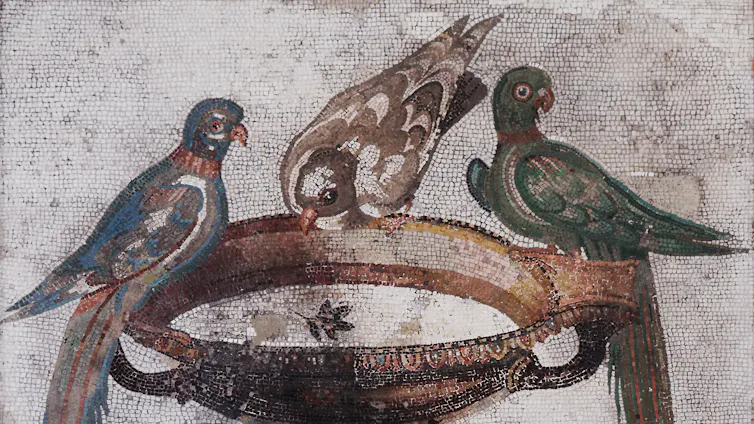 A tiled mosaic showing three birds drinking from a water fountain.