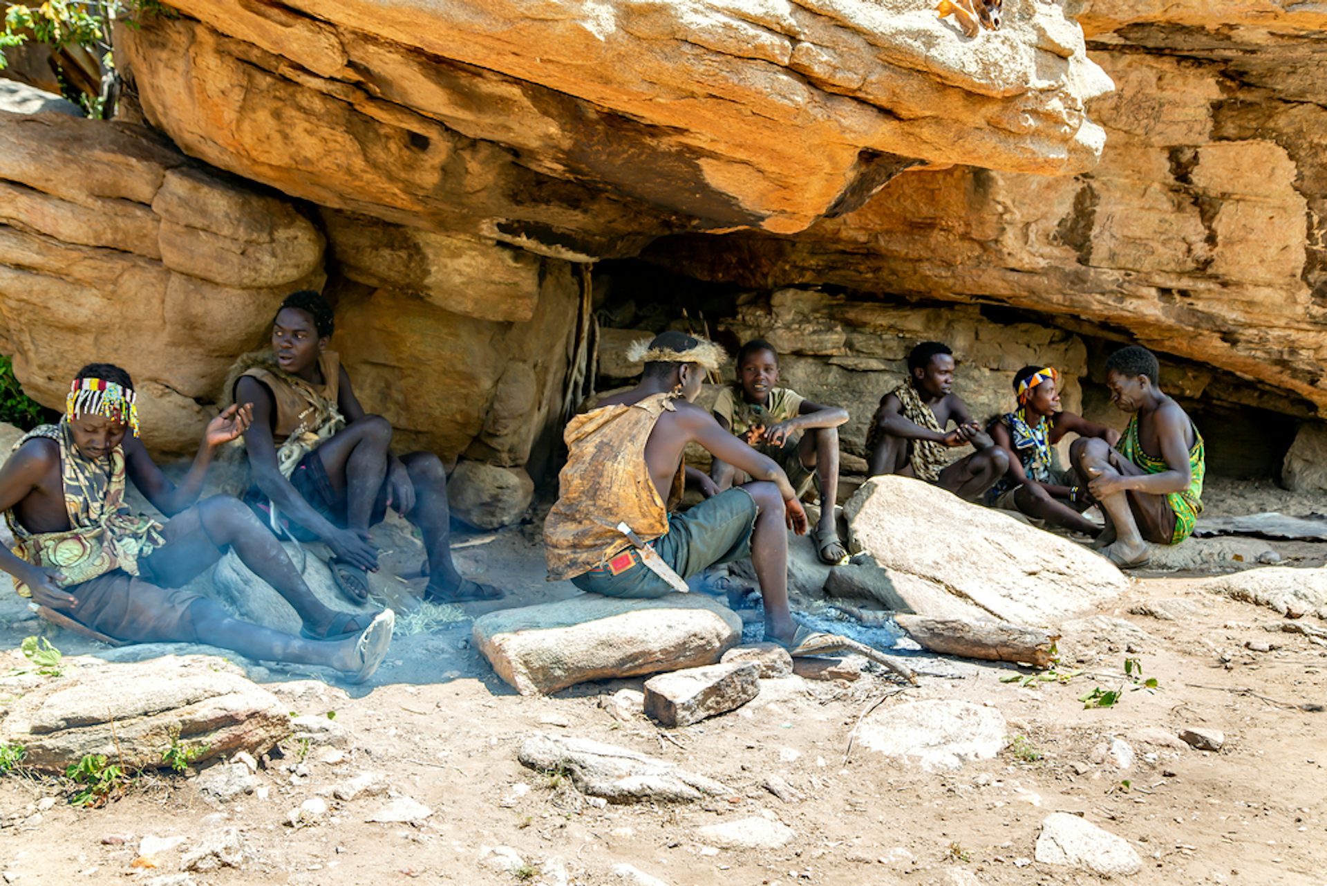 Members of the Hadza community sheltering from the sun under a rock overhang.
