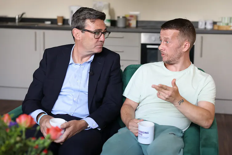 andy burnham having a cup of tea with a man in the kitchen of a supported accommodation centre.