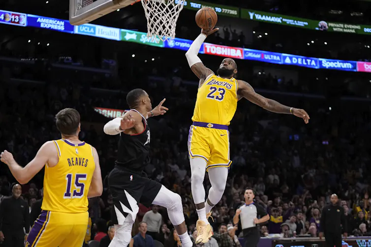 A basketball player in a yellow jersey prepares to dunk.