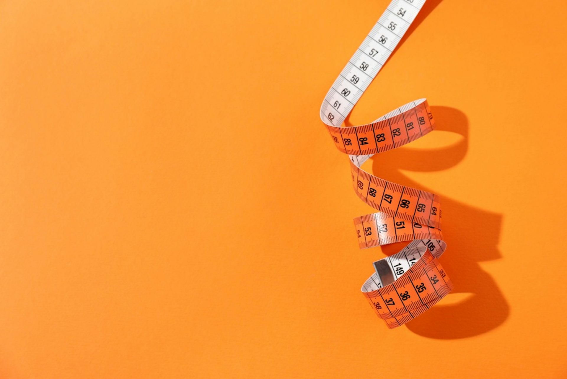 A tape measure against an orange background.
