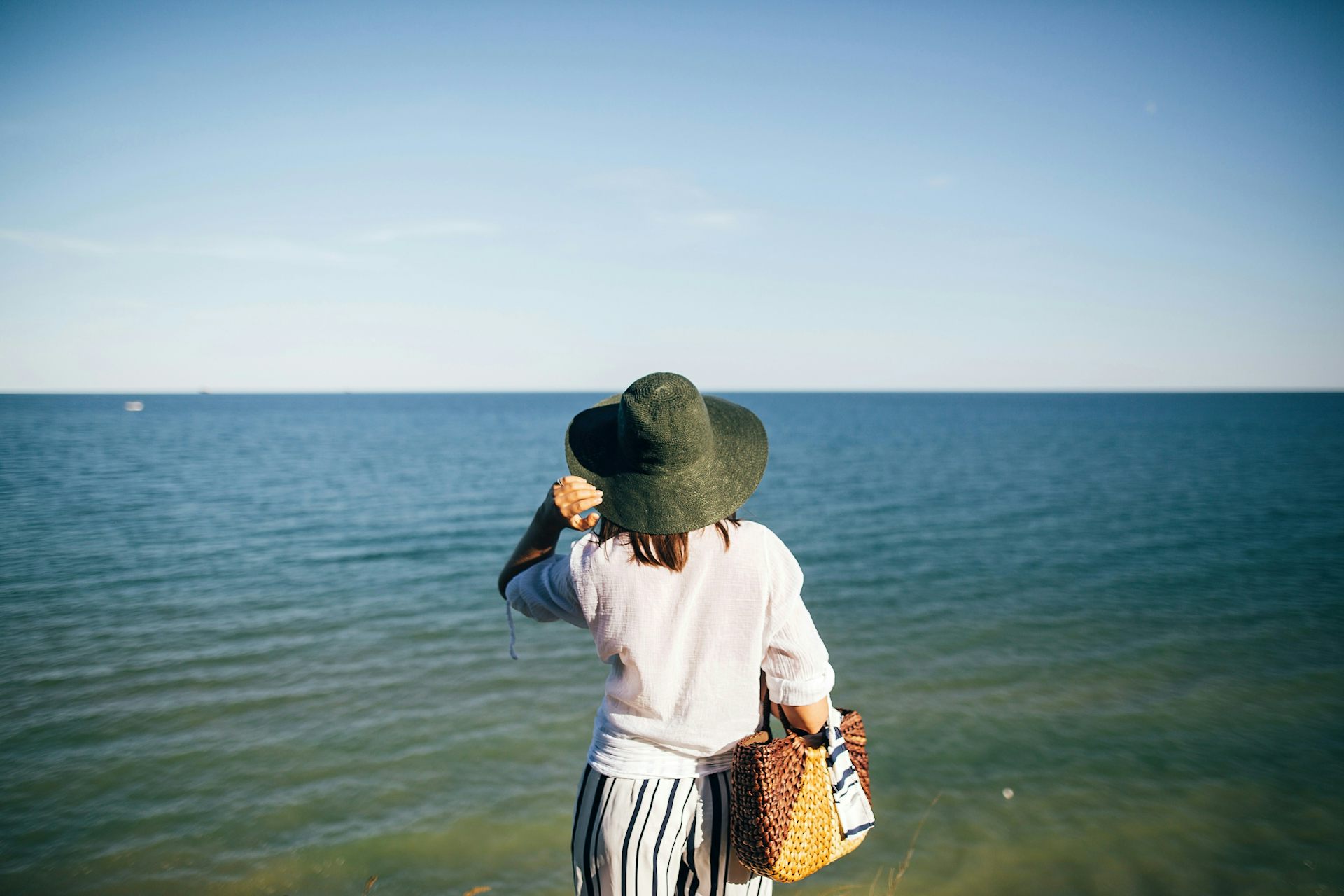 A woman seen from behind wearing a hat, and a white shirt with sleeves