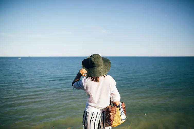 A woman seen from behind wearing a hat, and a white shirt with sleeves