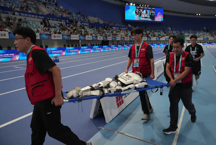 A humanoid robot is stretchered from the track after an accident.