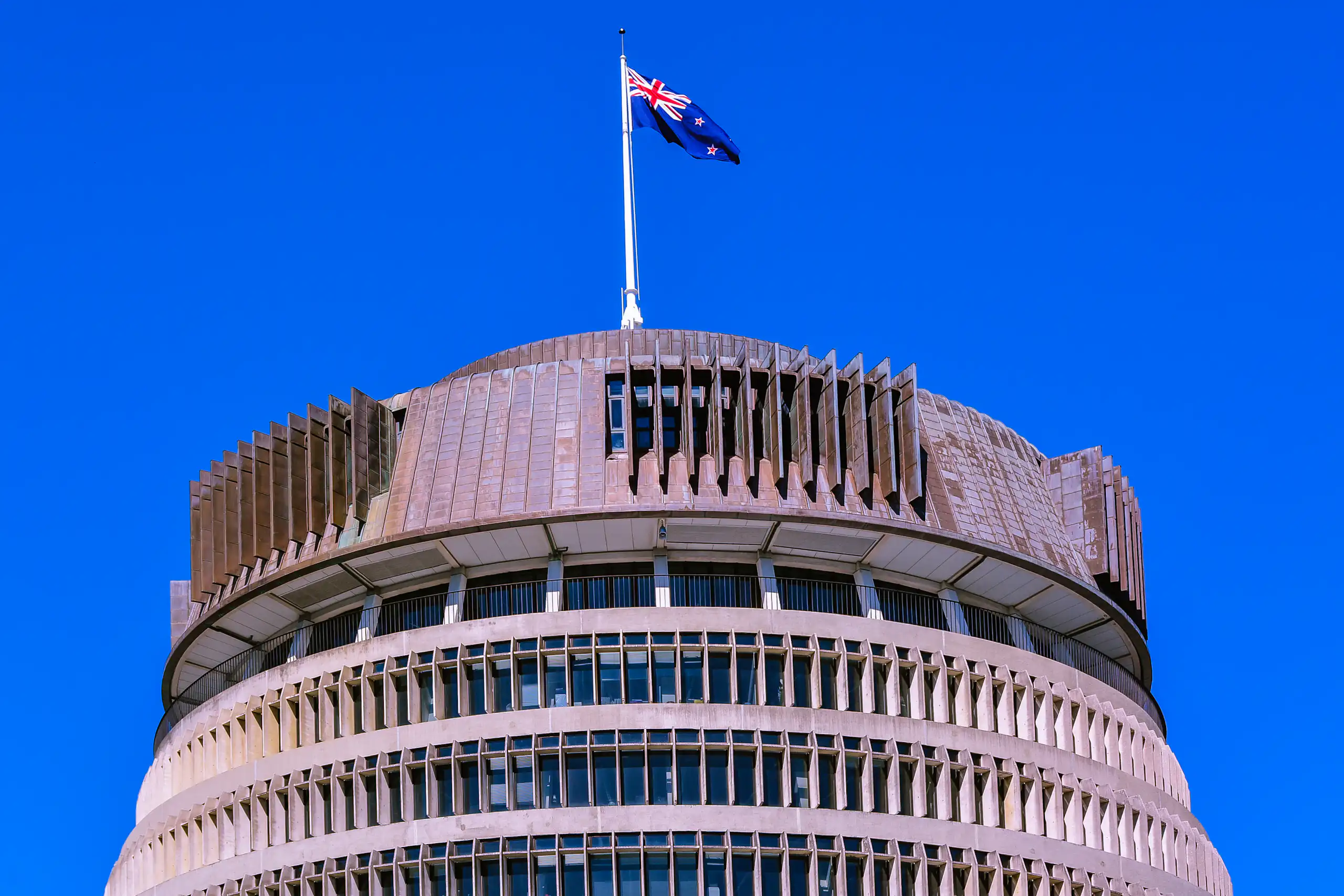 Beehive building in Wellington with flag flying against blue sky