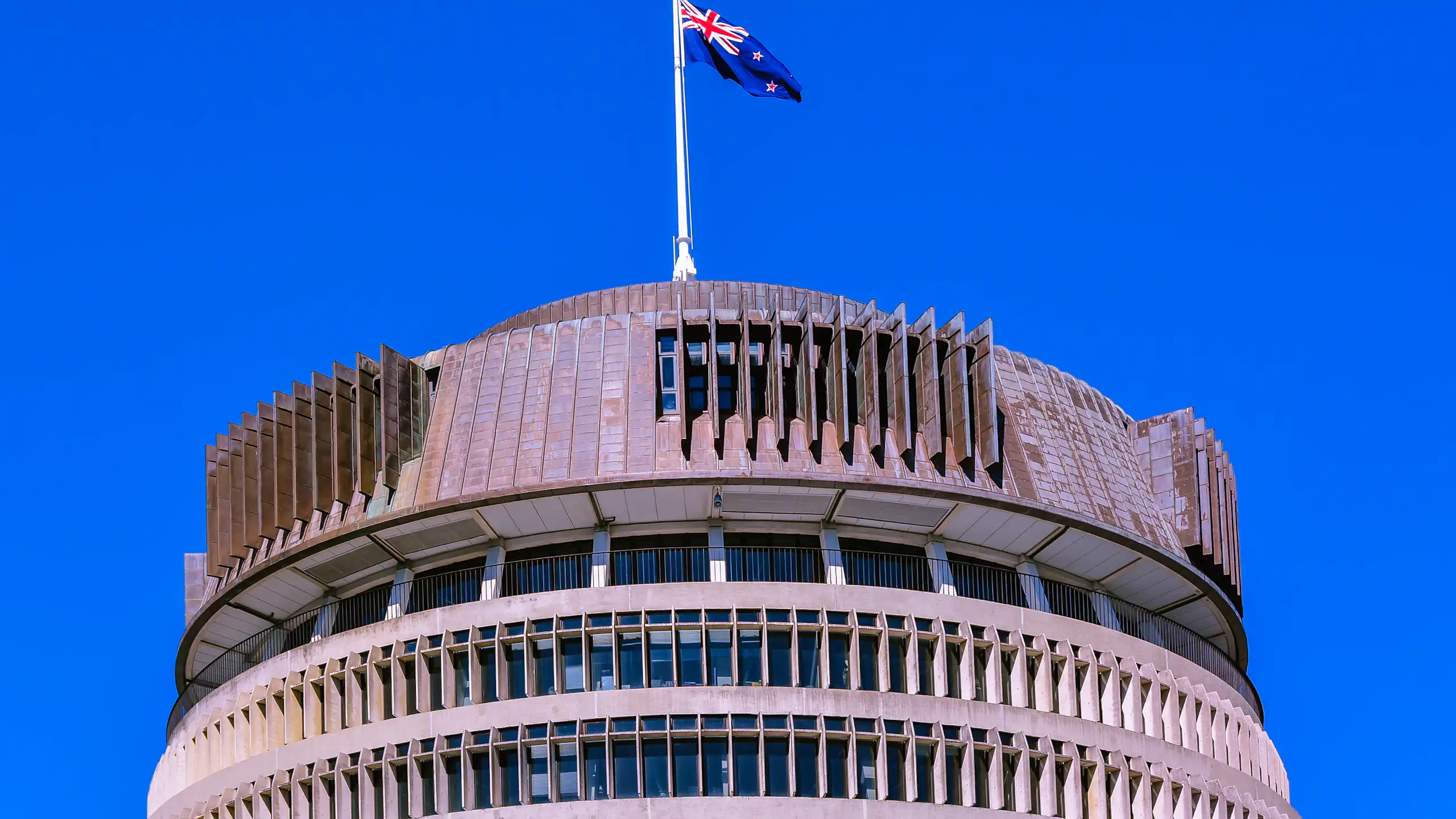 Beehive building in Wellington with flag flying against blue sky
