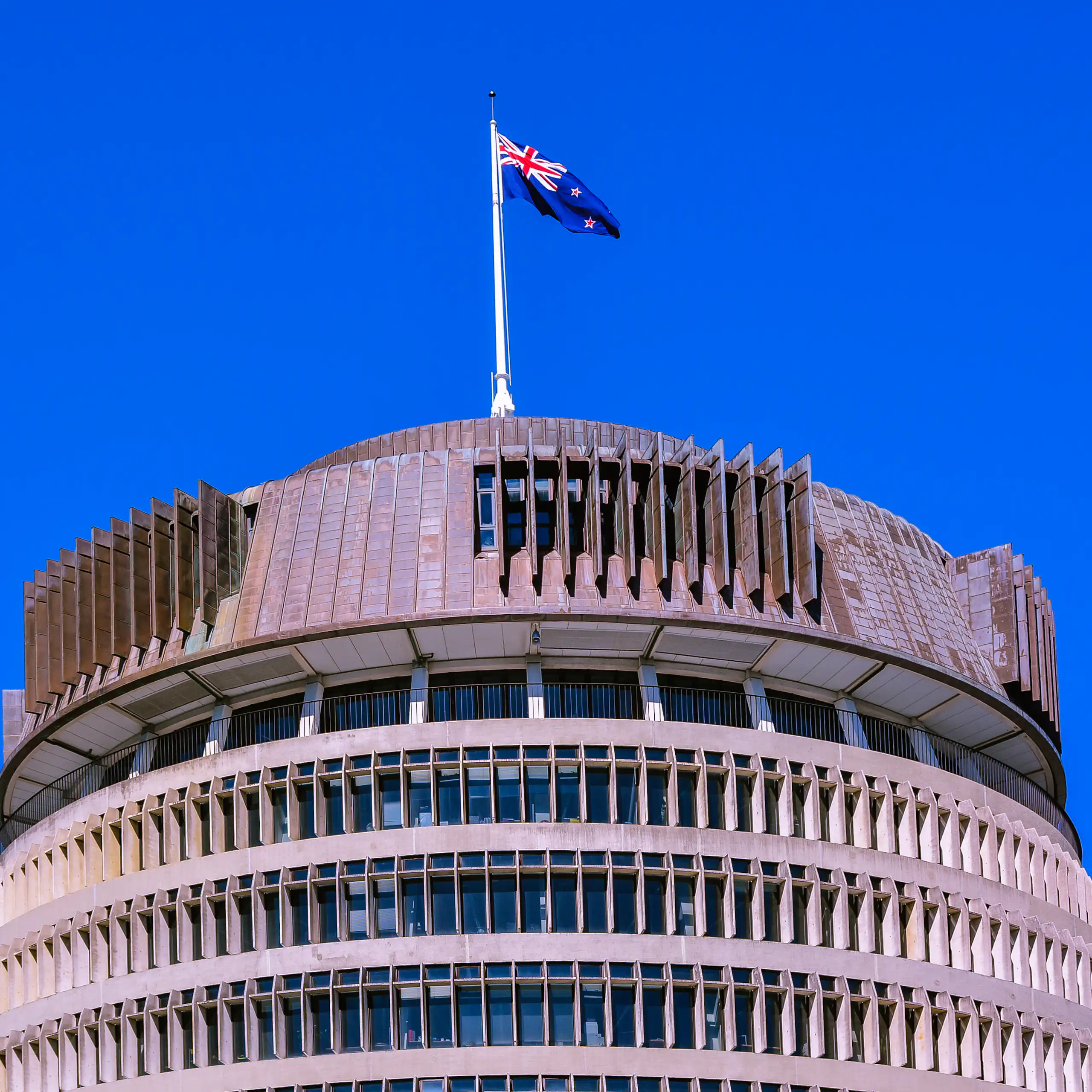Beehive building in Wellington with flag flying against blue sky