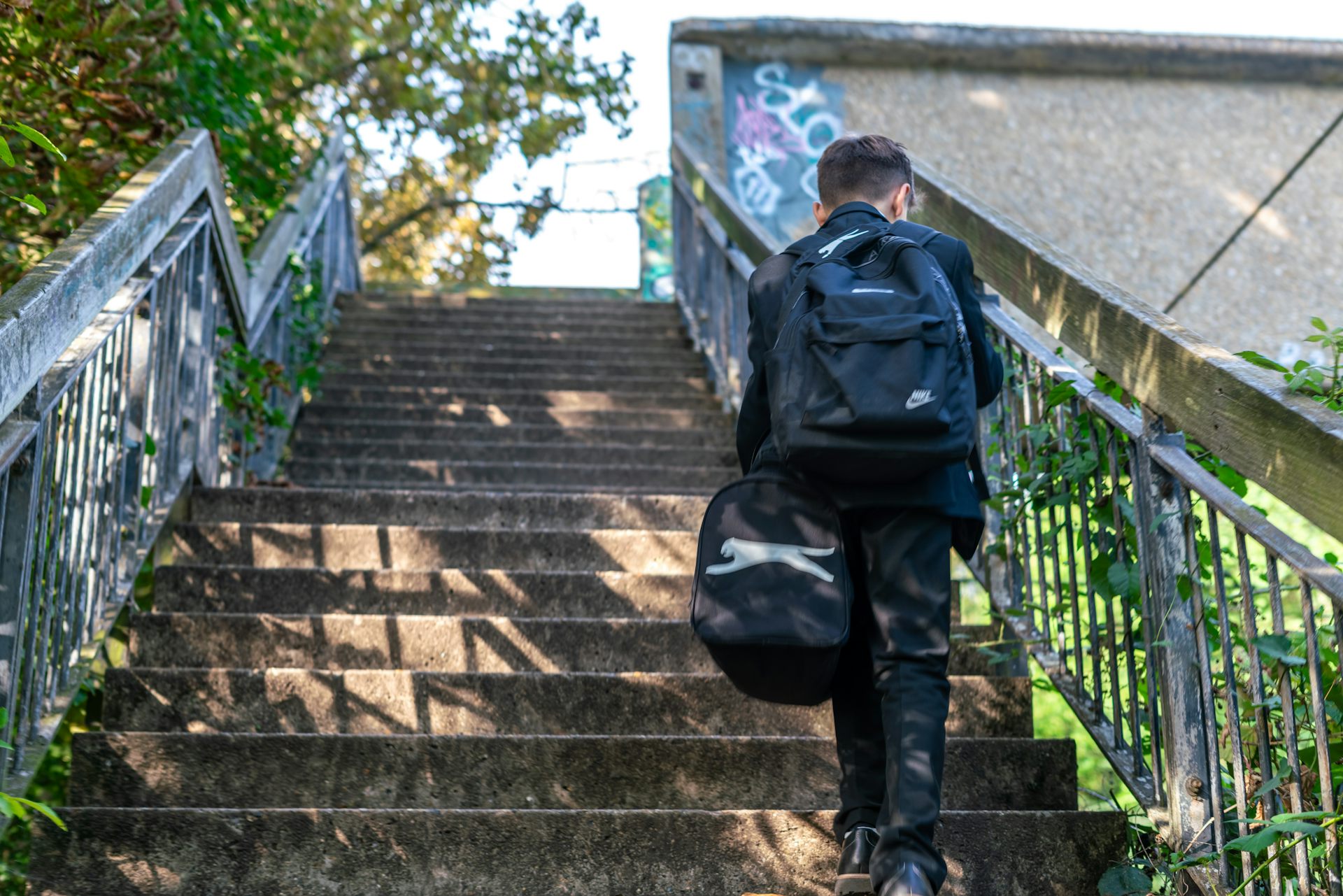 Boy in school uniform walking up steps.