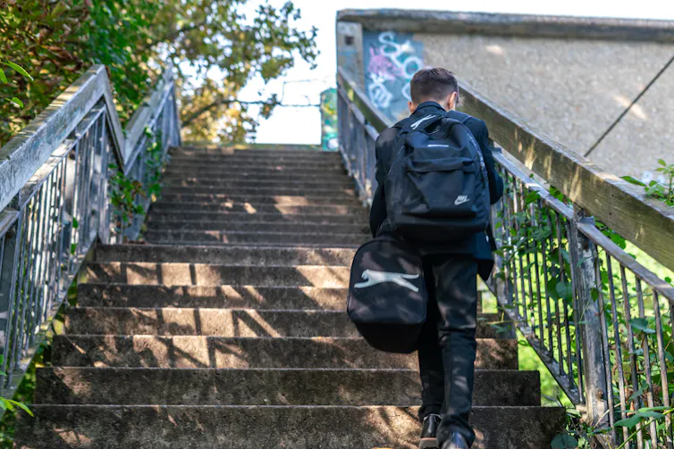 Boy in school uniform walking up steps.
