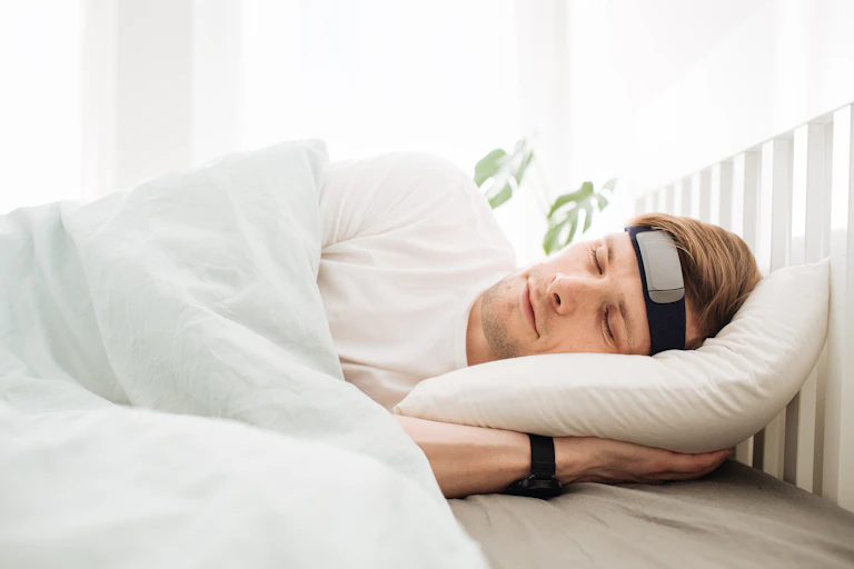 Man in his bed having trouble sleeping wearing a smart sleep band