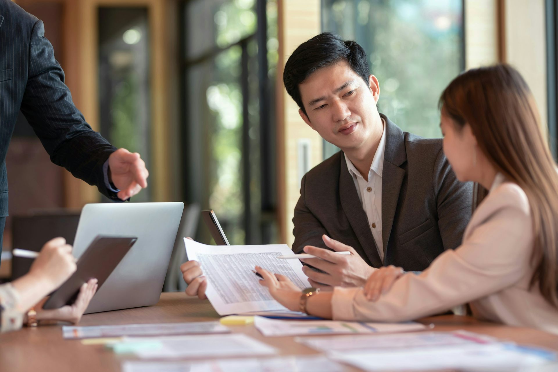 An asian man and woman review documents at a table