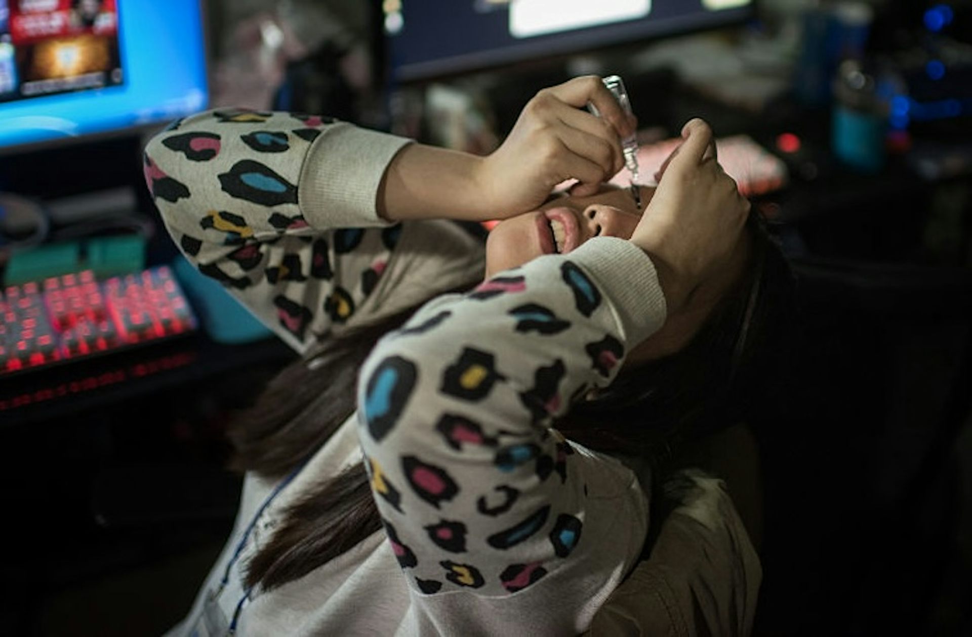 Young woman angles her head backward while she dispenses eye drops from a small bottle.