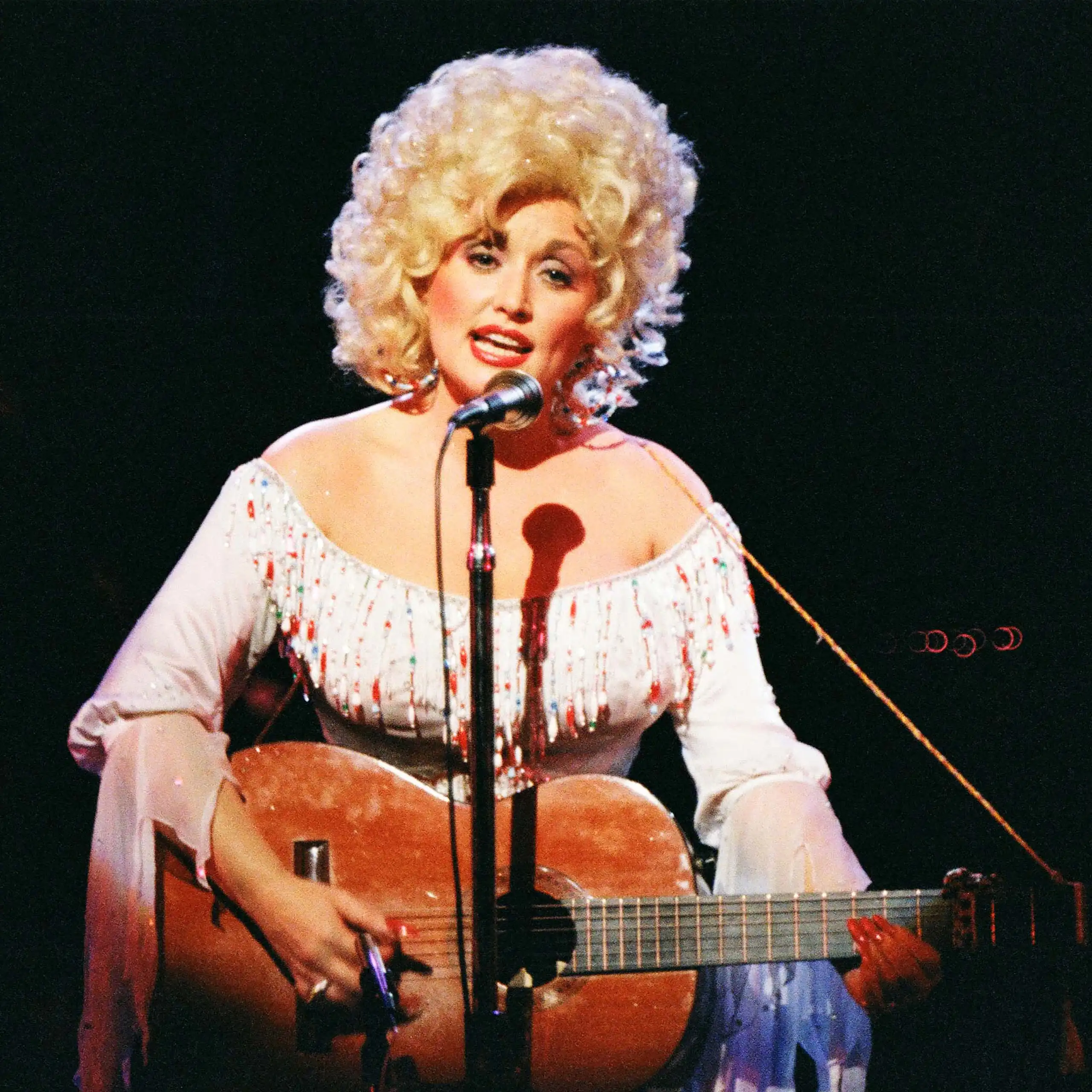Dolly Parton with guitar performing