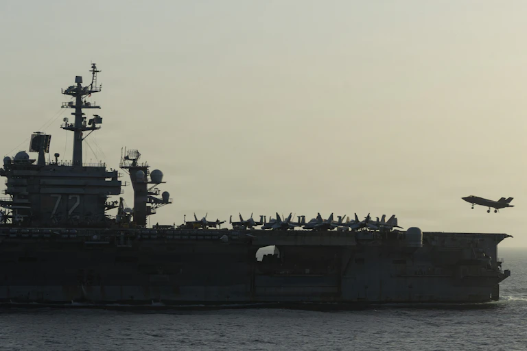 A warship is seen as a small aircraft lands on it.