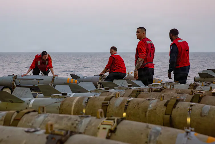Several men move ordnance on a warship.