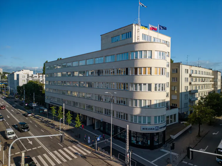 Imagen de un edificio con la esquina curvada que desemboca en una parte lisa y otra que se retrae.