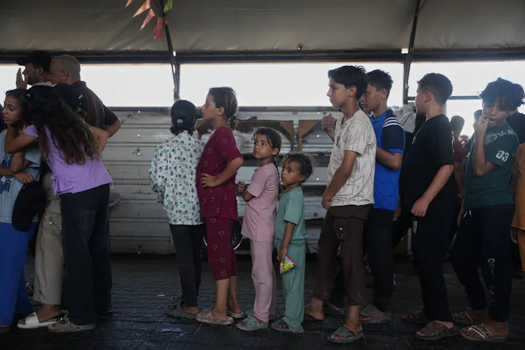 A group of children standing in line waiting to receive food.