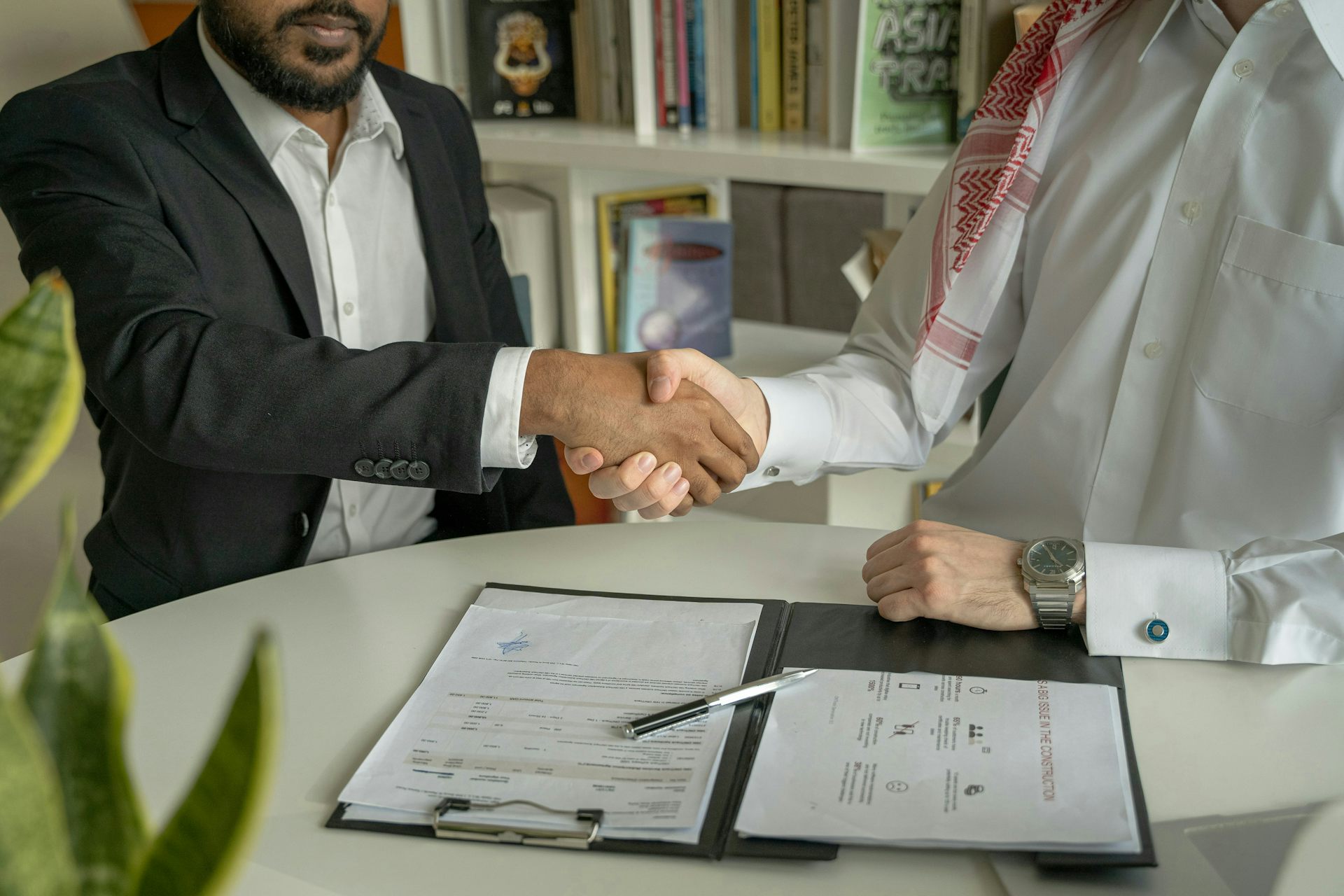 Two men shaking hands over signed documents