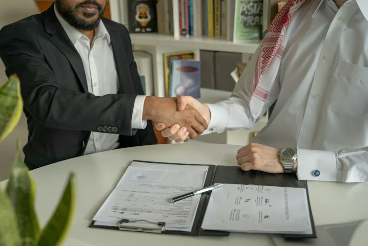 Deux hommes se serrent la main au-dessus de documents signés