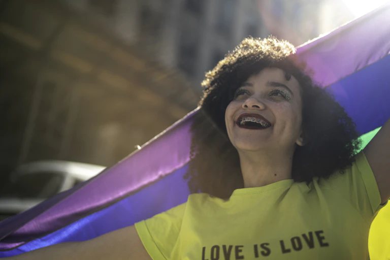 Teenage girl holding rainbow flag during pride parade.