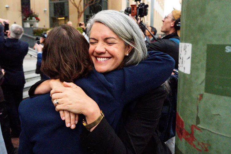 Two woman hugging and smiling.