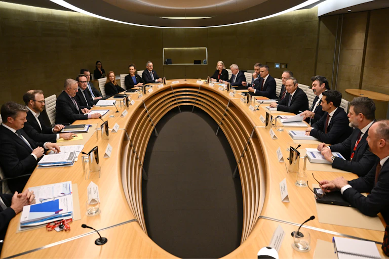A large oval table with politicians sitting around the outside