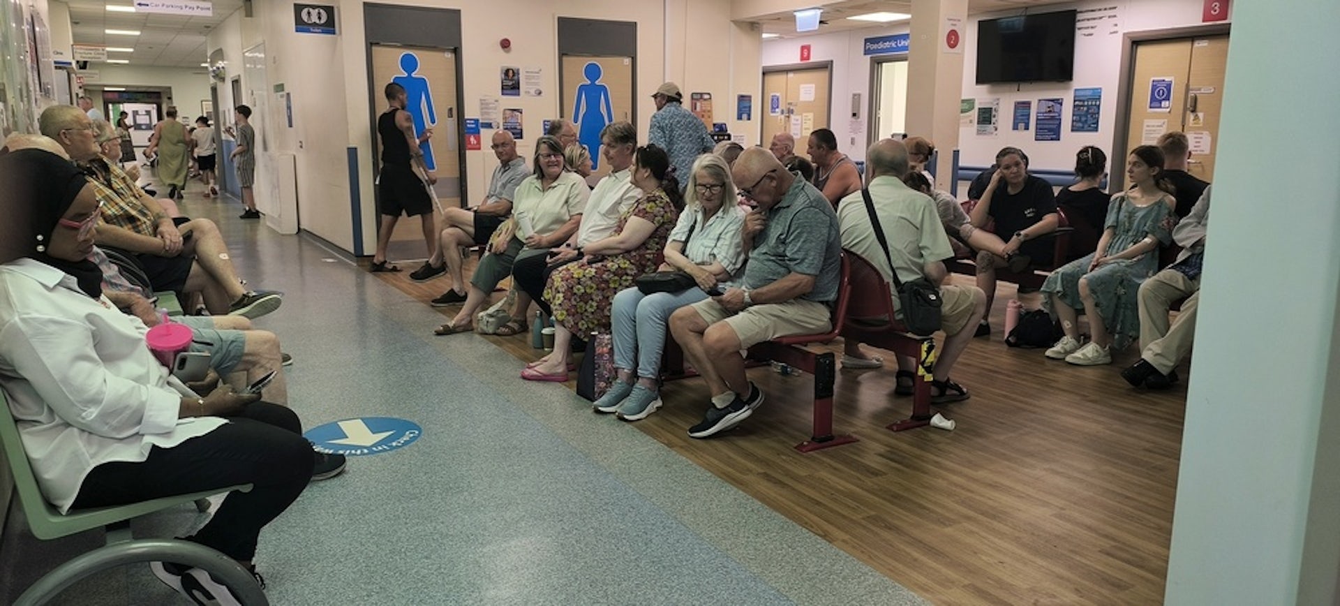 A crowded NHS hospital waiting room.