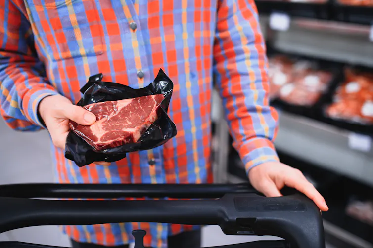 Prendre plus de protéines au petit‑déjeuner sans faire d’exercice ne vous fera pas gagner en masse musculaire – il faut distinguer la science du marketing 2 Dans un supermarché, un homme dépose un steak dans un caddy
