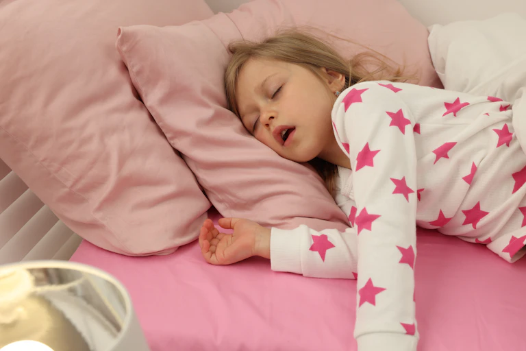 Little girl asleep in bed with mouth open