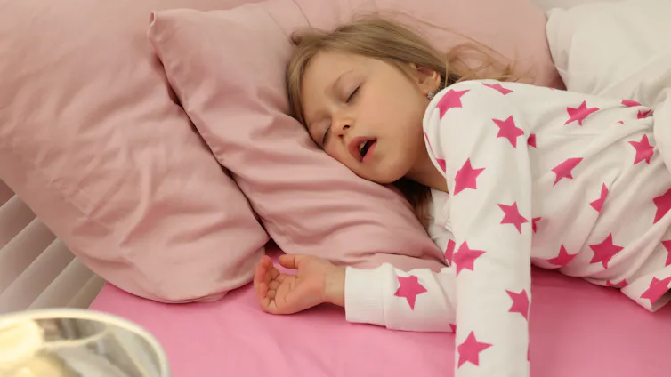 Little girl asleep in bed with mouth open