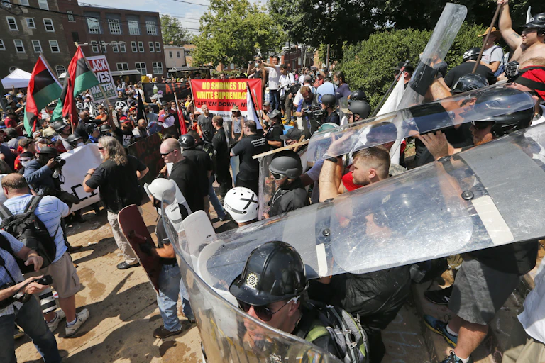 A crowd of people at a rally, fighting each other.