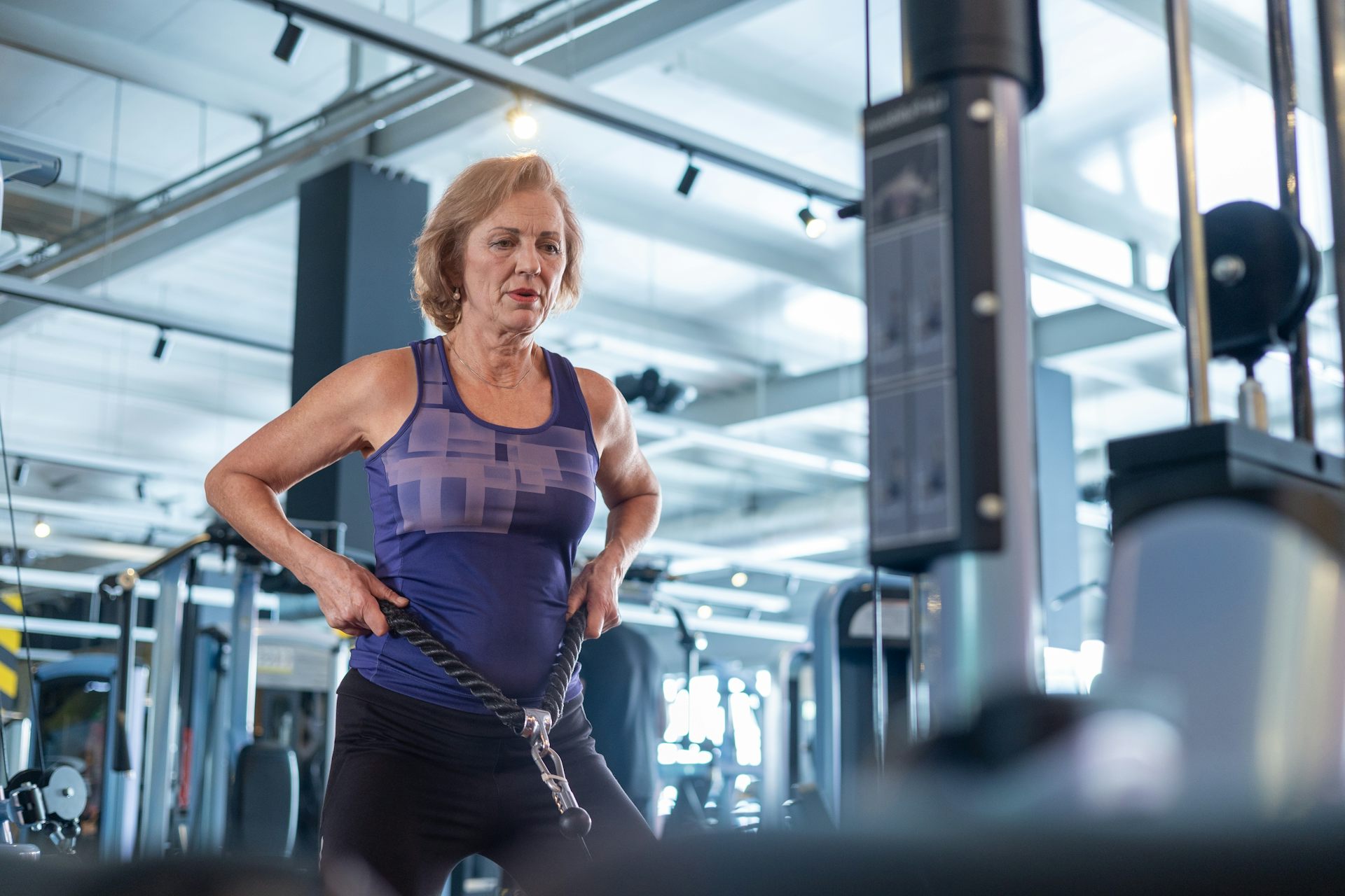 Un femme d’un certain âge s’entraîne avec câble dans un centre de fitness