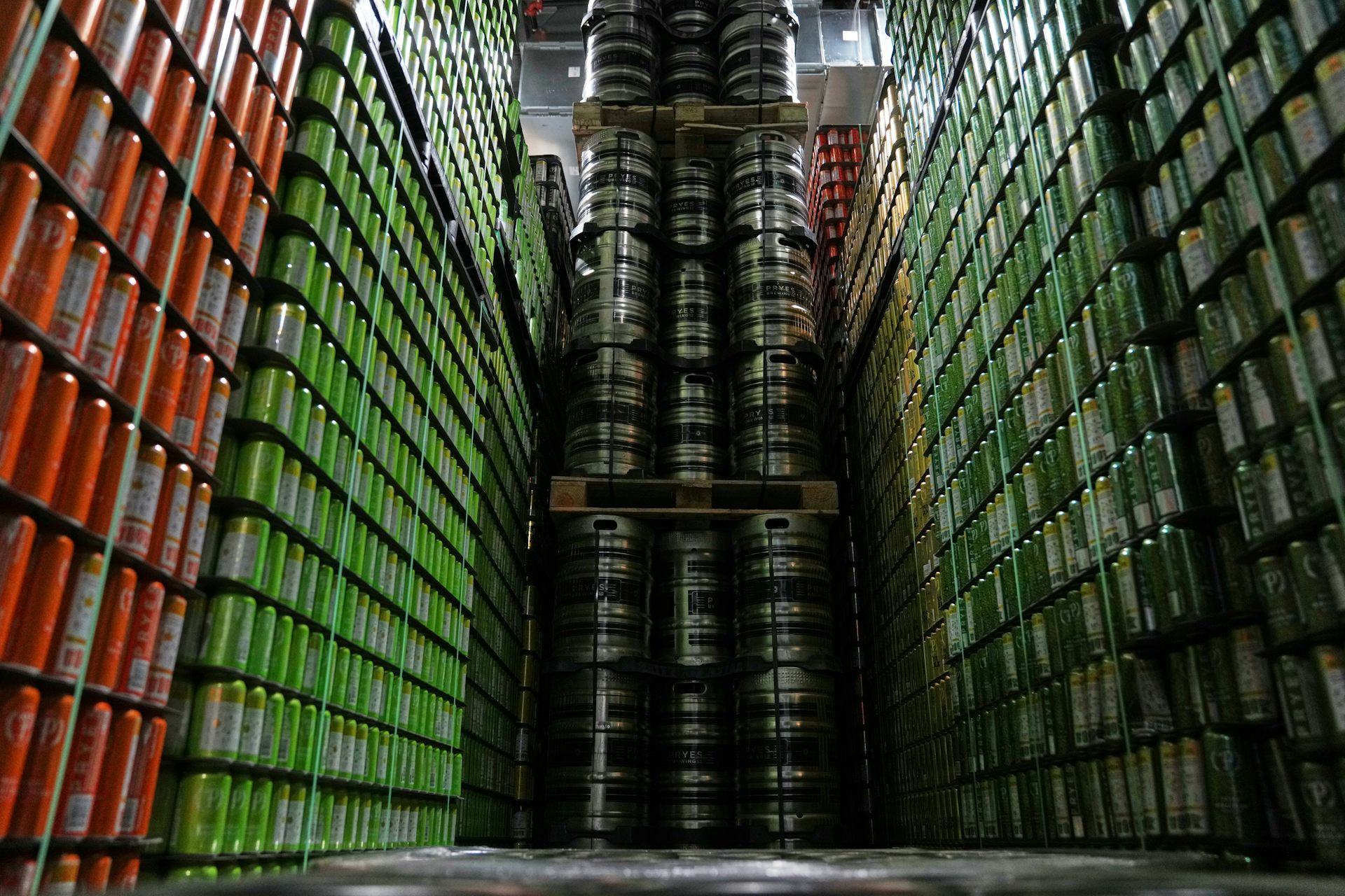 Cans and kegs of craft beer are stacked on top of one another in a warehouse