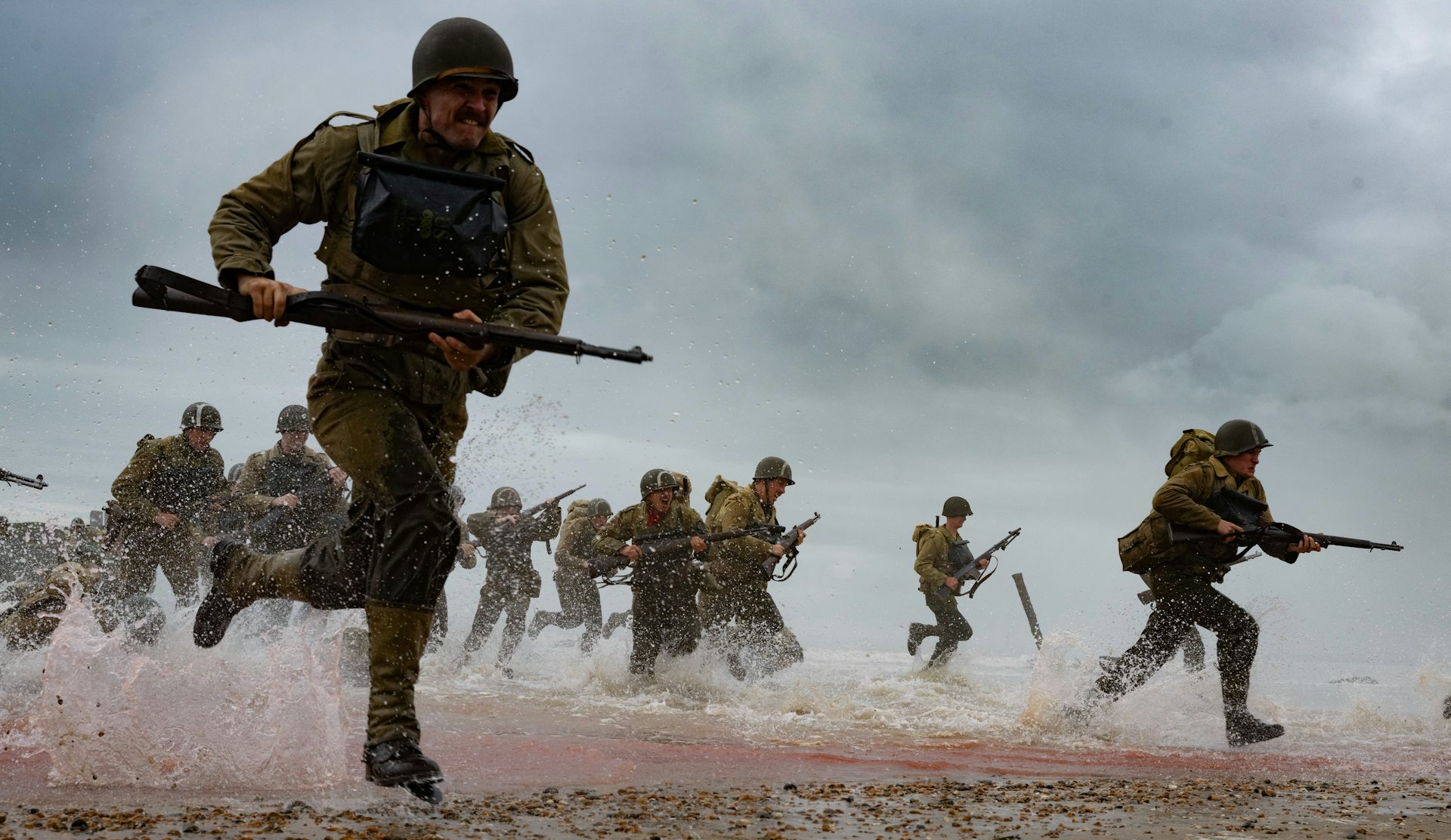 Soldiers running on a beach during D-day.