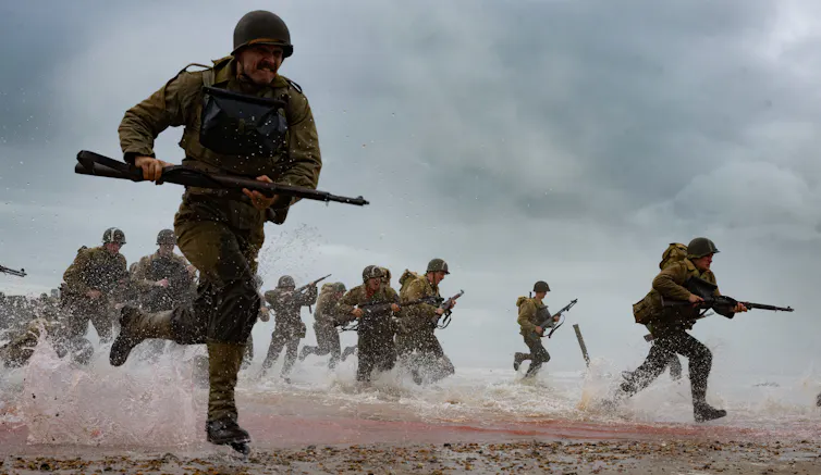 Soldiers running on a beach during D-day.