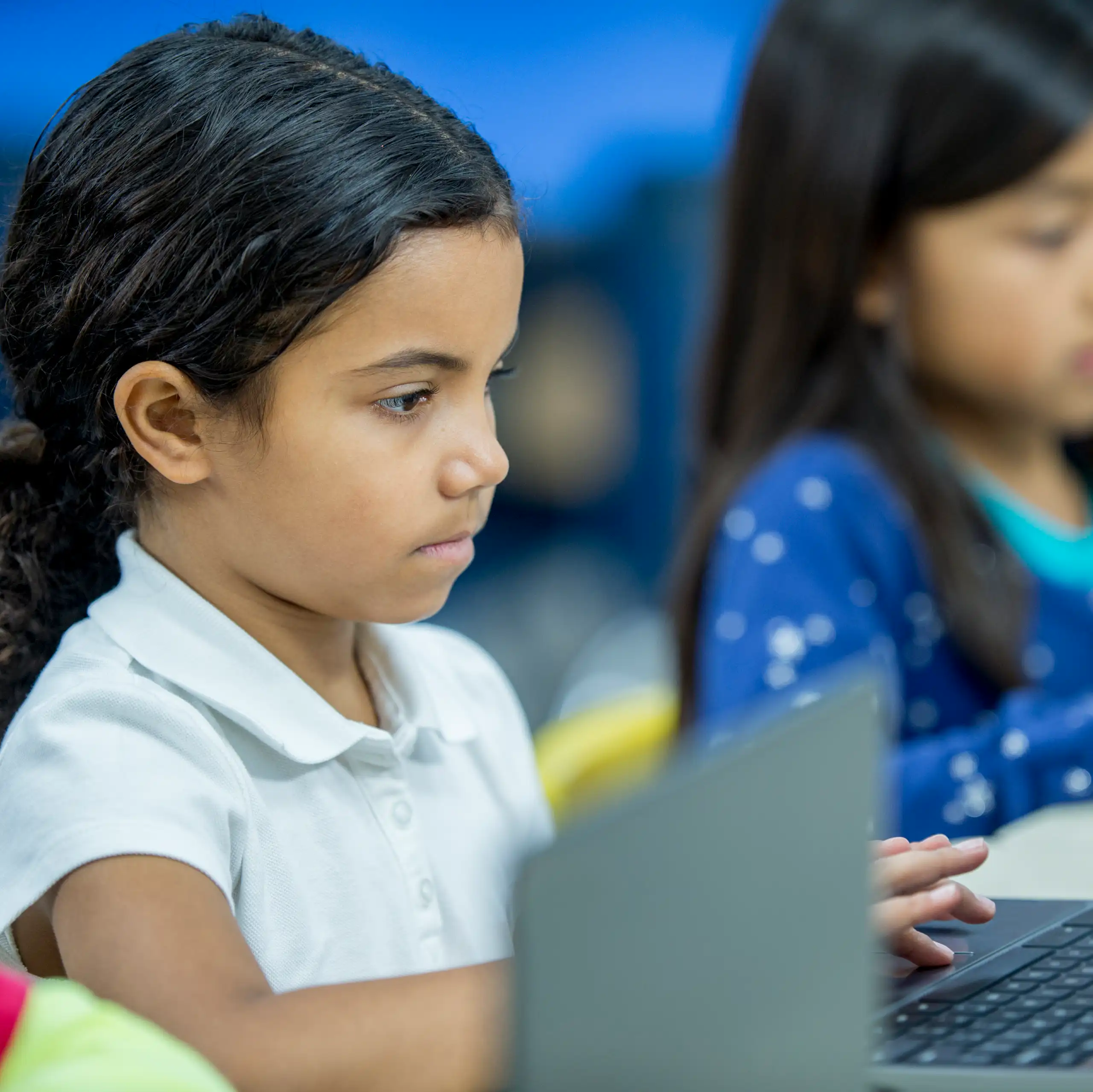Two lower elementary school students work on laptops