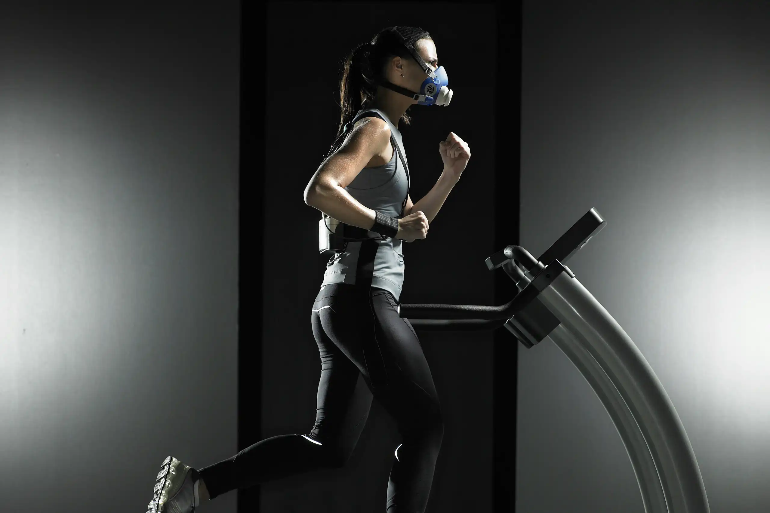 A woman wearing sensing equipment running on a treadmill