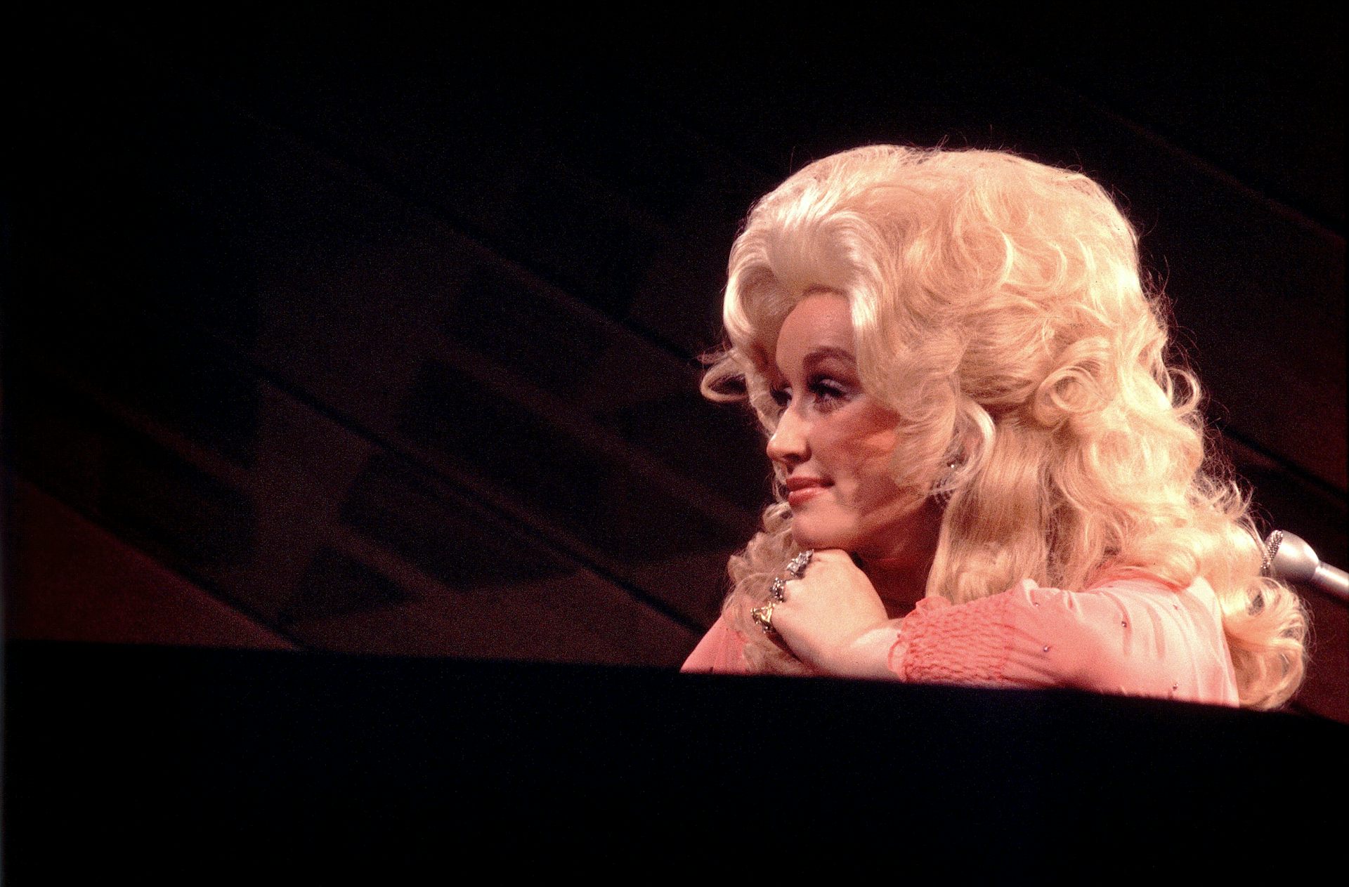 Woman with billowing, blonde hair gazes to her left while slyly grinning.
