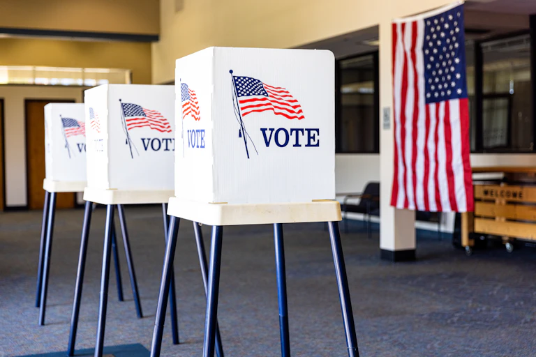 Three voting booths and an American flag.